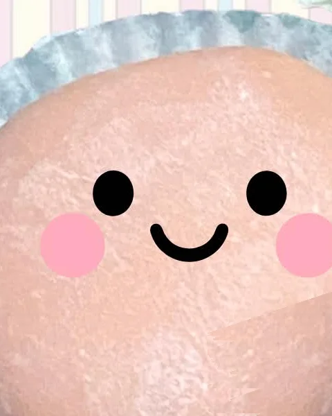 A pink ichigo mochi in its paper cup, dusted with starch, with a smiling face drawn on